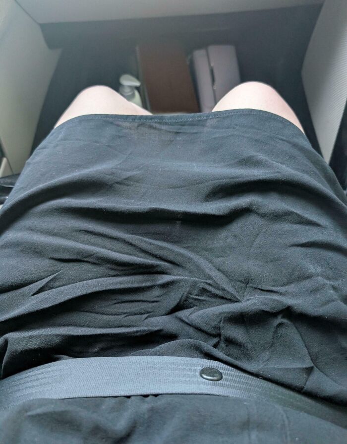 Wrinkled black skirt and a tight seat causing discomfort, illustrating mildly infuriated people’s ruined mood moment.
