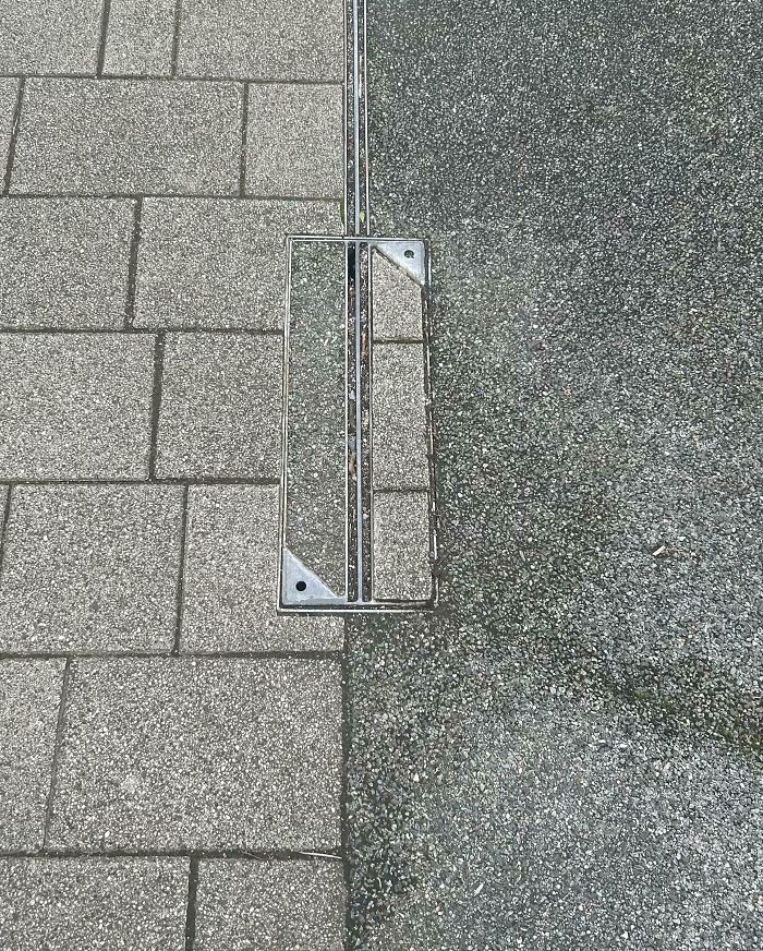 Uneven sidewalk with a metal grate that doesn't align, showing a common detail that ruined mood for mildly infuriated people.
