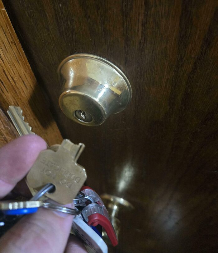 Hand holding a key that does not fit a brass door lock, an example of mildly infuriated people sharing what ruined their mood.