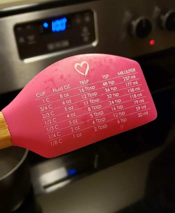 Pink spatula with cooking measurement conversions, showcasing clever ways people solved overlooked kitchen issues.