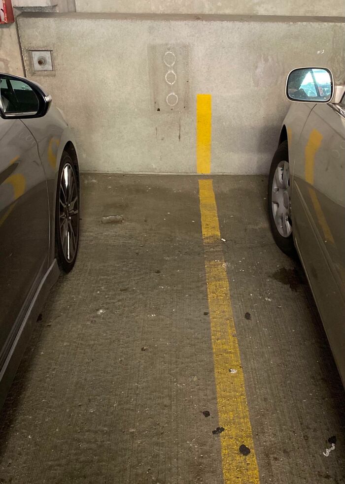 Parking space with a yellow line painted unevenly on the concrete floor showing clever ways people solved issues overlooked.
