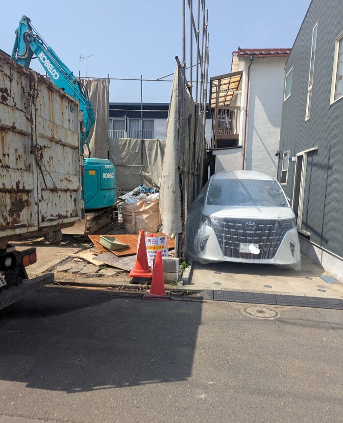 Car covered with plastic film parked beside a construction site showcasing clever solutions for overlooked issues.