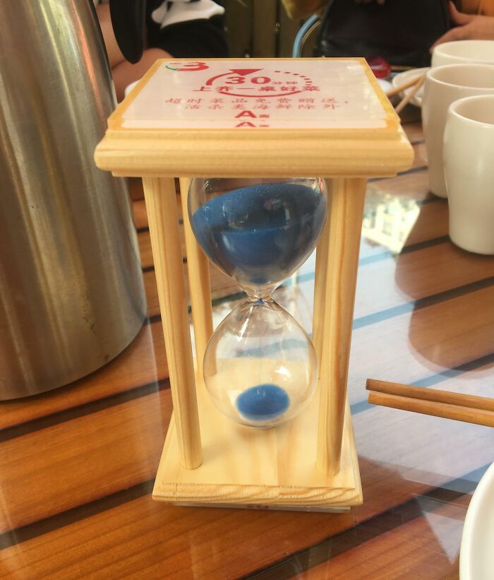 Hourglass timer with blue sand on a wooden frame, a clever solution for overlooked timing issues in daily settings.