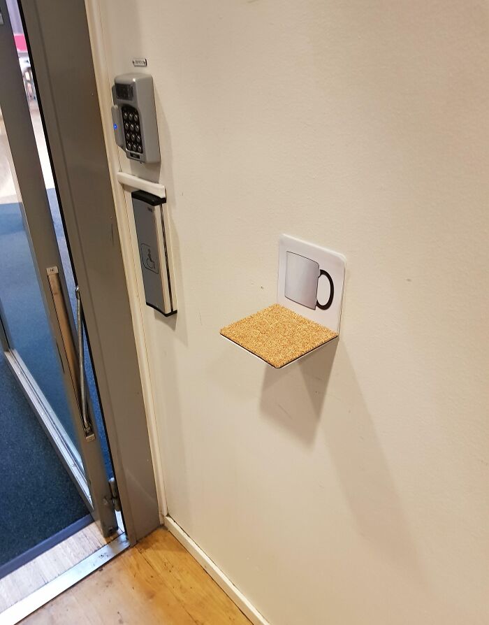 Small wall-mounted shelf with a mug icon designed as a clever solution for holding cups near an entryway keypad.