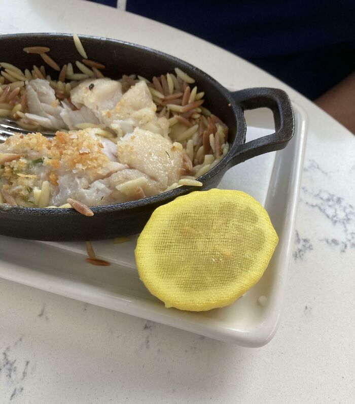 Cast iron skillet with cooked fish and rice next to a yellow mesh cover, showcasing clever solutions to overlooked issues.