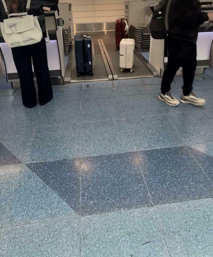Two travelers at airport baggage claim with cleverly arranged suitcases on conveyor belt for easy pickup.