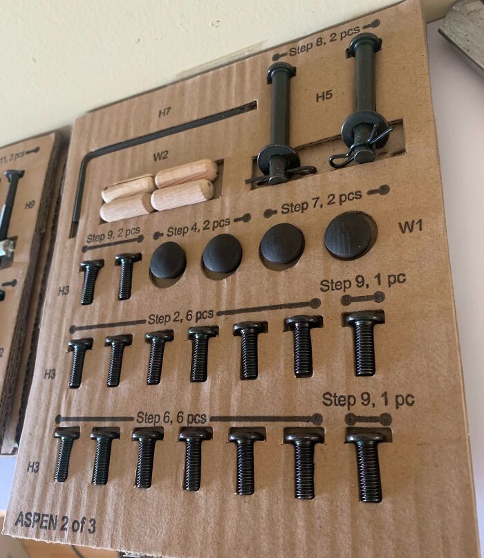Organized hardware pieces on cardboard labeled with steps, showcasing clever ways people solved overlooked assembly issues.