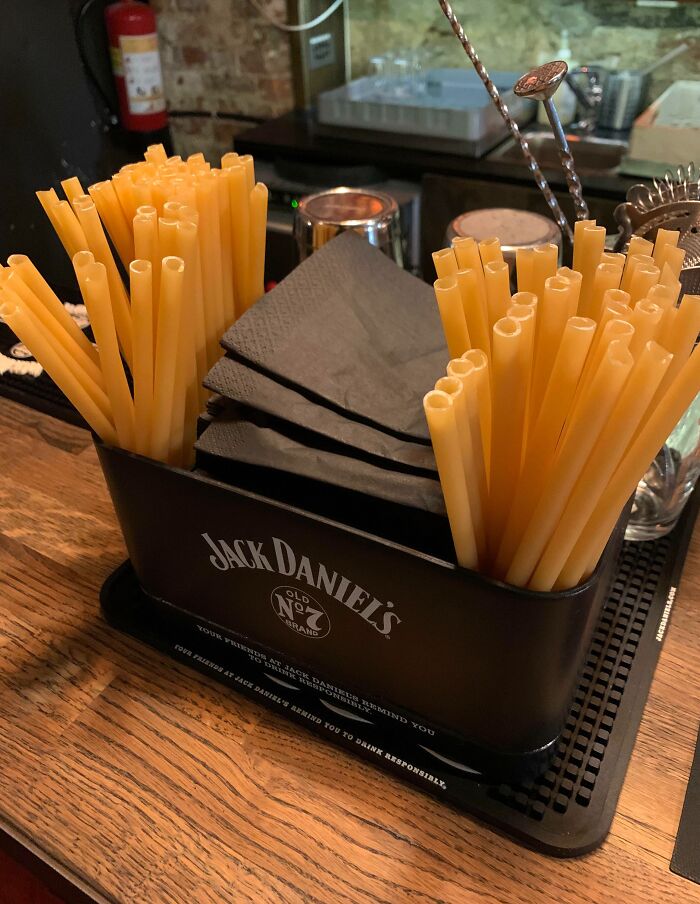 Bar counter setup with cleverly organized plastic straws and napkins in a Jack Daniel's branded holder.