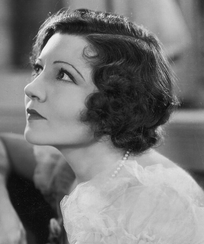 Black and white portrait of a glamorous 1940s icon with vintage hairstyle and pearl necklace, epitomizing Hollywood glamour.