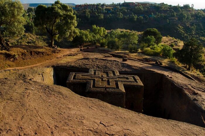 Carved rock church hidden in a landscape of trees and hills, showcasing unique UNESCO gems in a remote natural setting.