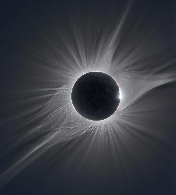 Solar eclipse with glowing corona and radiating light beams, showcasing a rare natural phenomenon in the sky.