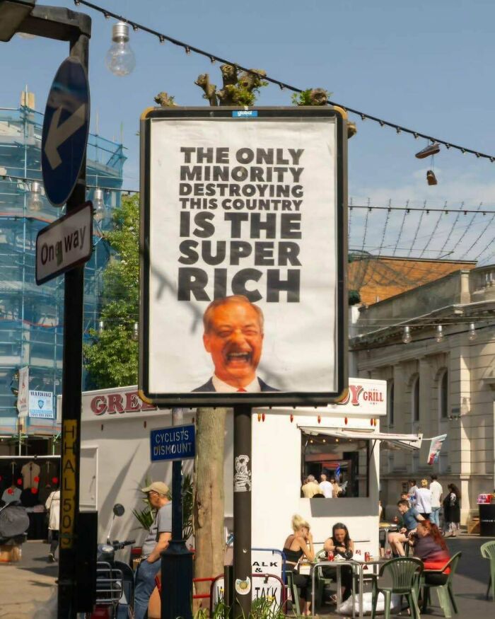 Street sign with a chaotic good message about the super rich and unhinged acts in an urban outdoor dining scene.