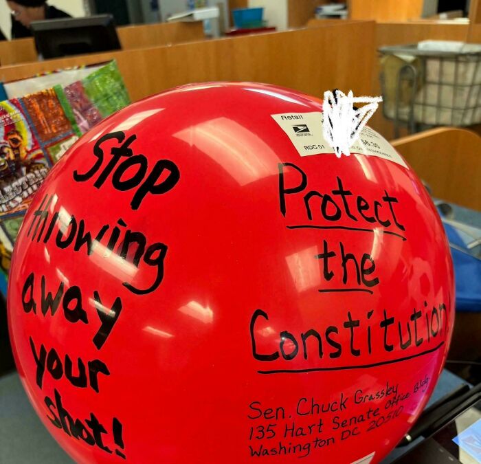Red balloon with handwritten messages encouraging to stop throwing away shots and to protect the Constitution, chaotic good acts.