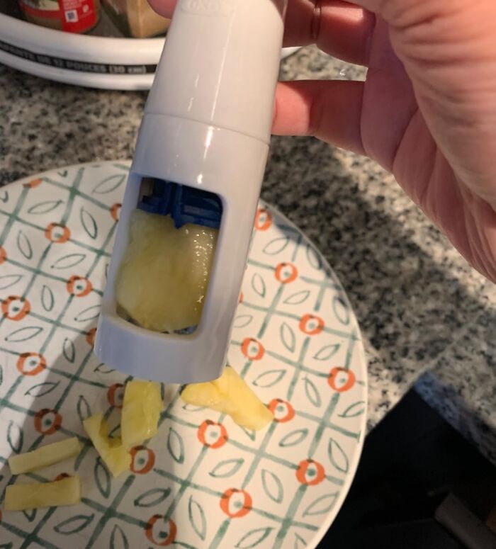 Hand using a gadget to squeeze lemon pieces on a patterned plate illustrating fancy lemonade ideas.