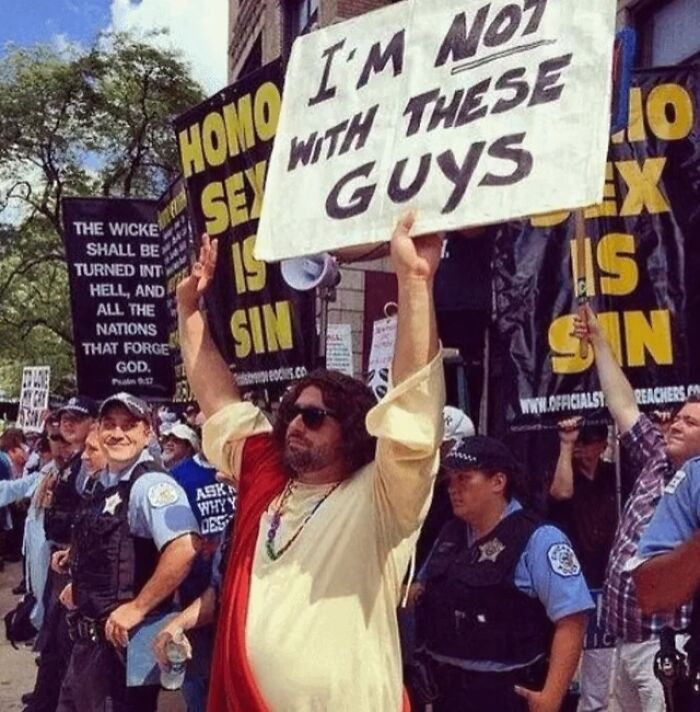 Man dressed as Jesus holding a sign at a protest, one chaotic good act with the best intentions at heart.