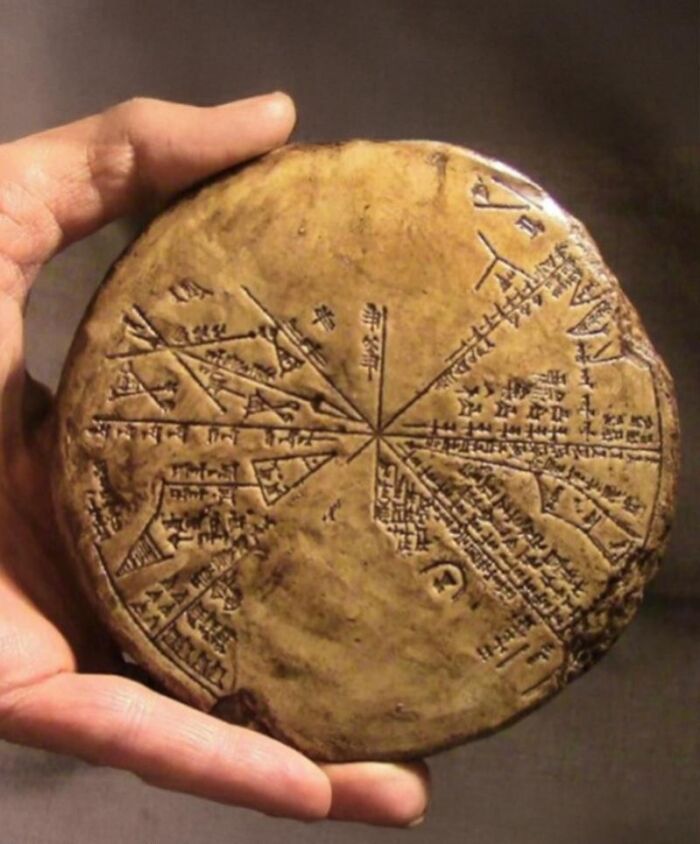 Ancient history artifact held in hand, featuring cuneiform script and star map engraved on circular clay tablet.