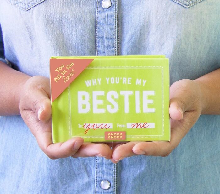 Person holding a green booklet titled Why You're My Bestie, a gift representing beautifully unhinged friendship.
