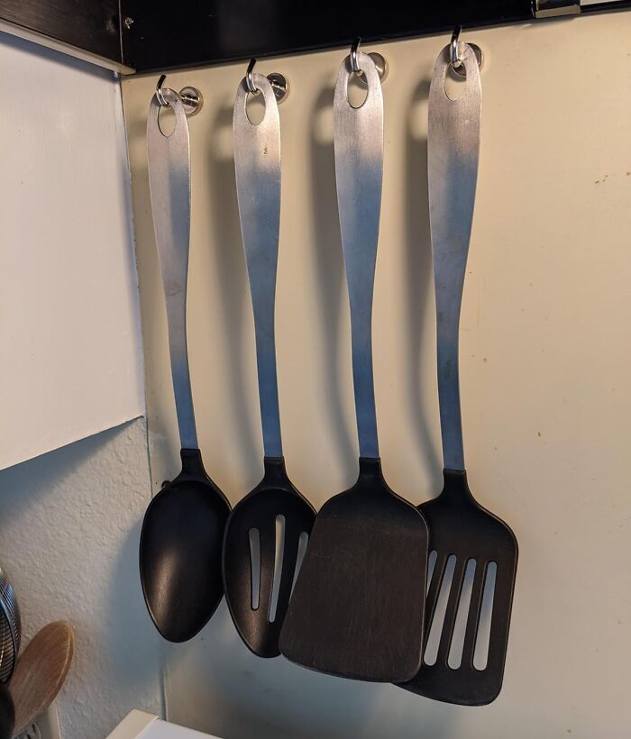 Kitchen utensils hanging on hooks in a compact space, demonstrating storage solutions for a shoebox kitchen.