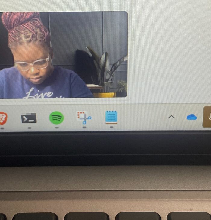 Person on a video call working from home displayed on a laptop screen with a keyboard in view, illustrating work-from-home memes.