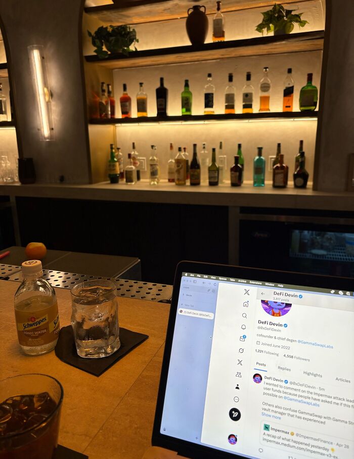 Laptop on bar counter with drinks nearby, illustrating funny work-from-home memes in a relaxed setting.