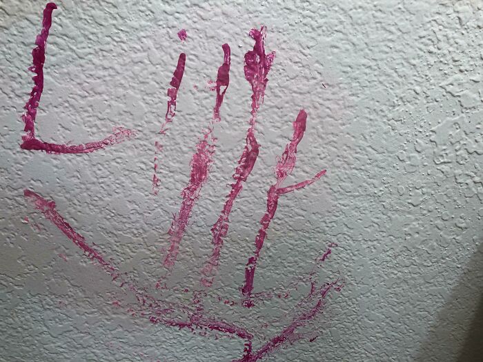 Dibujo en la pared hecho con pintura rosa, mostrando marcas de manos infantiles y garabatos. Padres y madres enfrentan situaciones así.