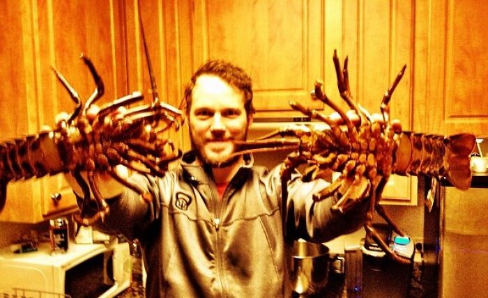 Man in a kitchen holding two large lobsters, a nostalgic Instagram post showcasing celebrities' past moments.