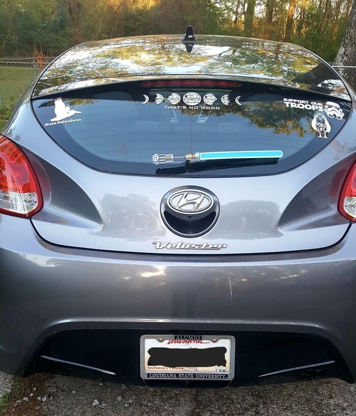 Rear view of a gray Hyundai Veloster with Star Wars themed decals and a lightsaber Father's Day gift accessory.