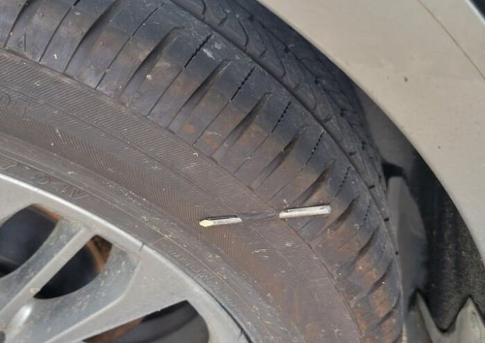 Car tire with a nail lodged in the tread, showing a common bad luck moment on Friday the 13th.