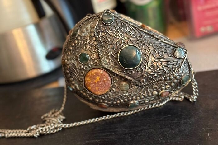 Intricately designed thrifted find with colorful stones and detailed metalwork, a weird and wonderful vintage collectible.