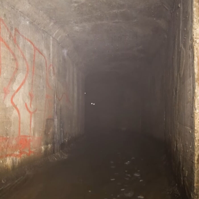 Dark abandoned tunnel with eerie glowing eyes in the distance, evoking chilling ghost encounters atmosphere.