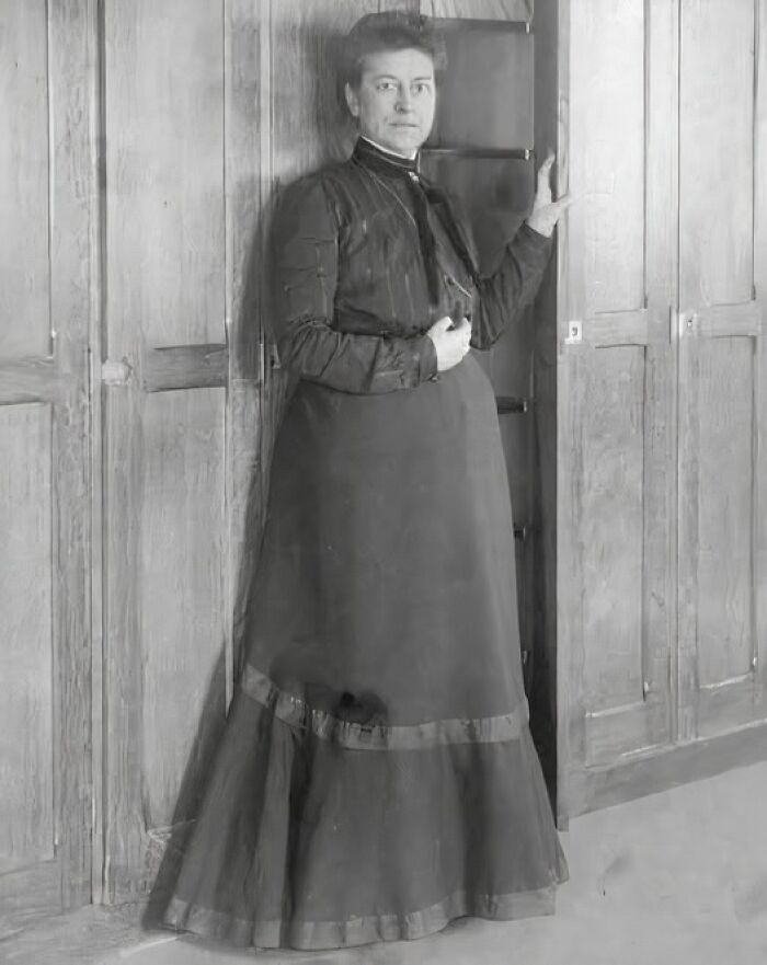 Black and white photo of a woman standing by wooden cupboards, illustrating unusual wonderful or tragic facts that happened.