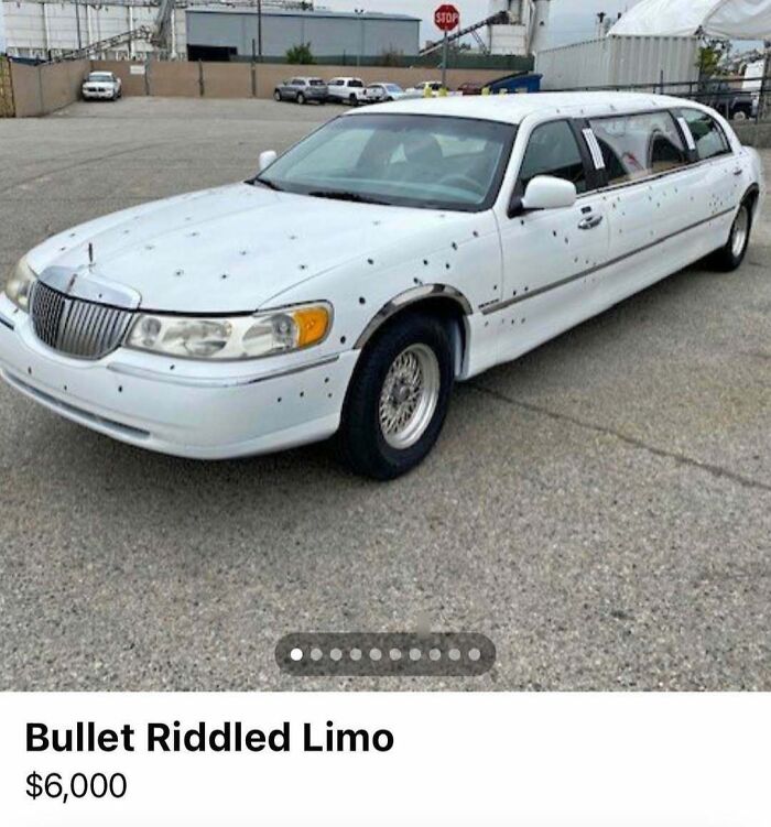 White bullet-riddled stretch limo parked in a lot, one of the chaos cars spotted for sale with visible damage.