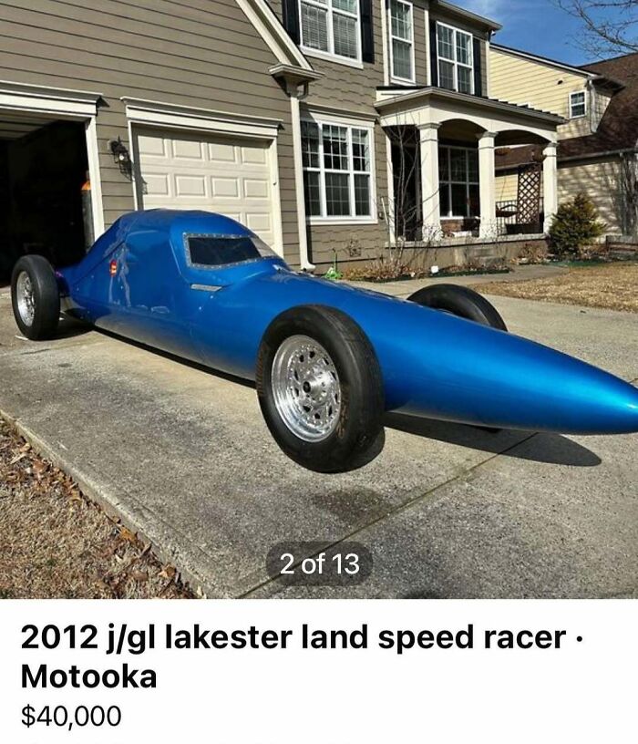 Blue 2012 Lakester land speed racer car parked in residential driveway among chaos cars for sale.