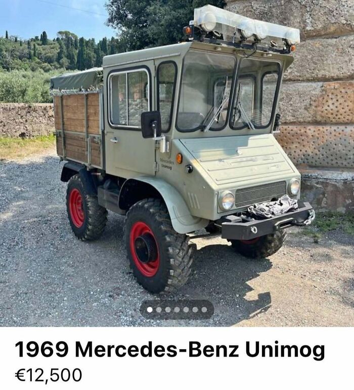 Vintage 1969 Mercedes-Benz Unimog truck with red wheels parked outdoors in chaotic car sale collection.