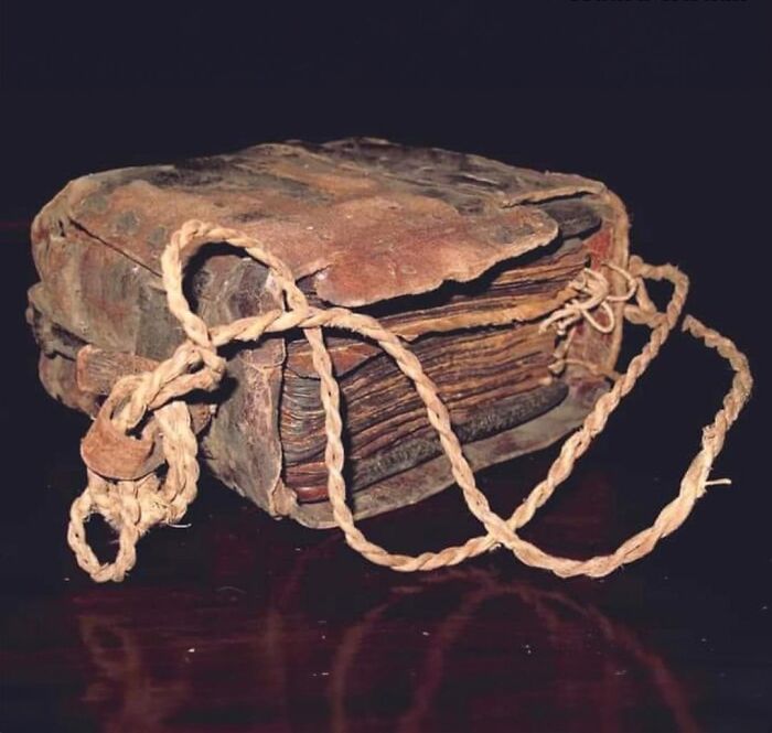 Ancient history artifact showing a worn, bound manuscript with a braided cord, highlighting historical preservation.