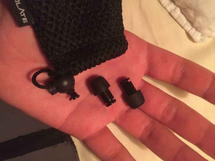 Small black earbud tips held in an open hand next to a black mesh pouch, demonstrating life hacks for everyday use.