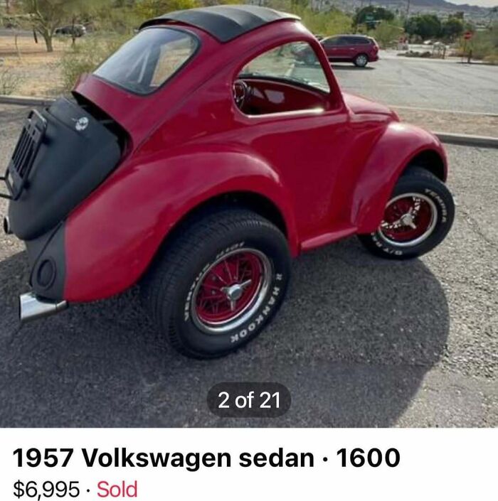 Red customized 1957 Volkswagen sedan with oversized tires parked outdoors, featured among cars of absolute chaos for sale.