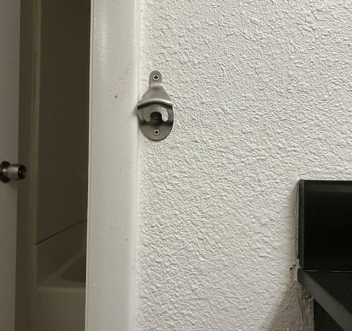 Wall-mounted bottle opener installed near a bathroom door, showcasing a simple hotel design decision.