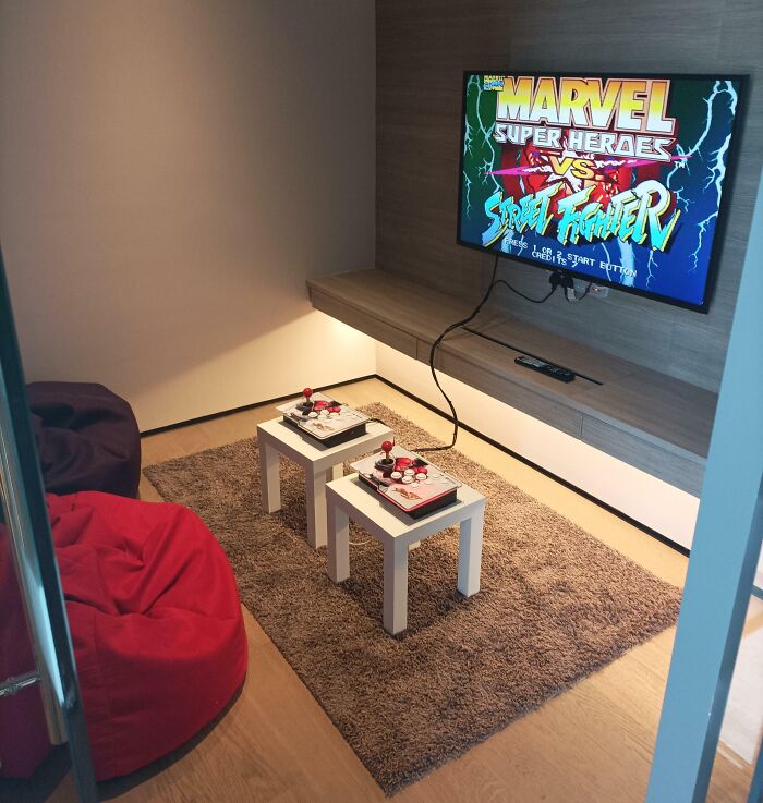 Creative hotel design featuring a cozy gaming corner with bean bags, arcade controllers, and a wall-mounted TV setup.