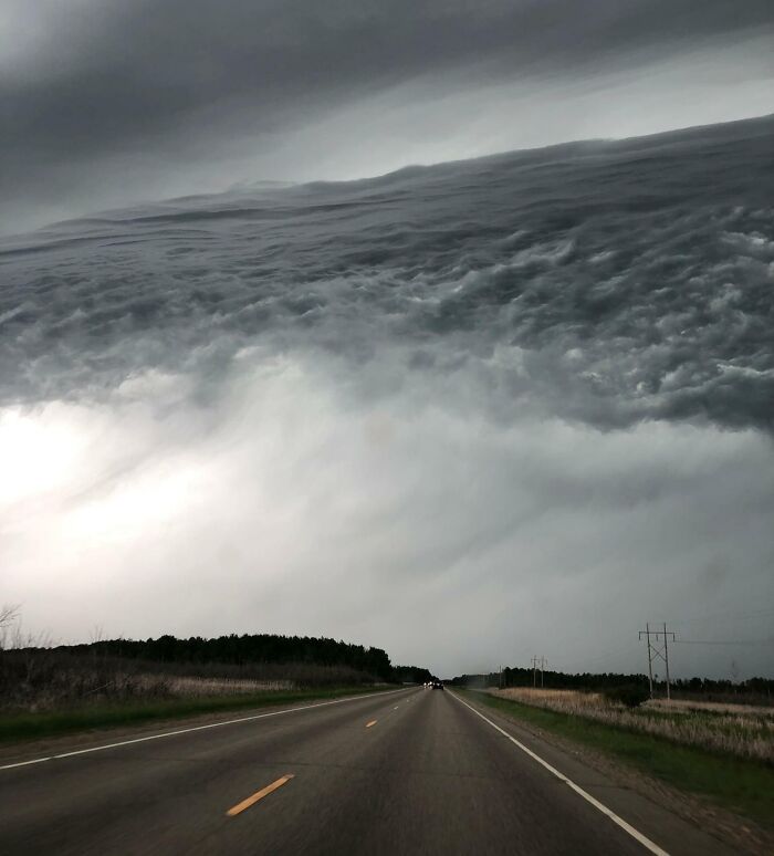 Unusual cloud formation over a rural road creating a surreal scene requiring a double take to realize what it really is.