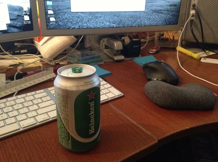 Work-from-home setup with a can of beer on desk, dual monitors, keyboard, mouse, and office supplies around the workspace.