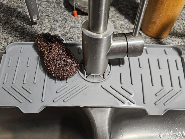 Kitchen sink area with a modern faucet and a mat holding a scrubber, showcasing refreshing kitchen organization ideas.