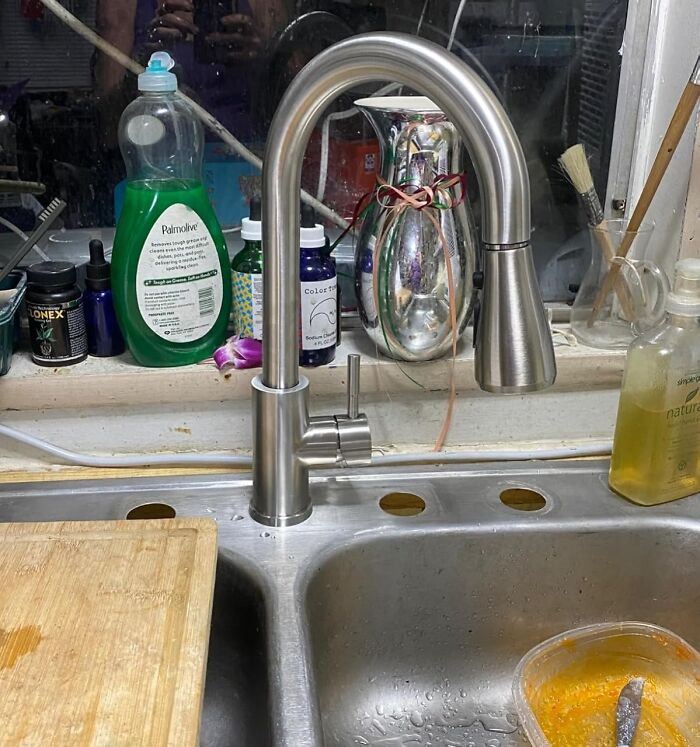 Modern kitchen sink faucet with cleaning supplies and a wooden cutting board, highlighting ideas to give your kitchen a glow-up.