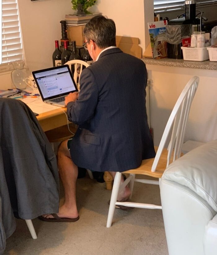 Man working from home in a blazer and shorts, sitting at a desk with a laptop, illustrating work-from-home memes humor.