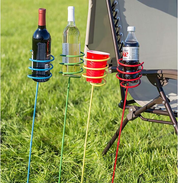 Colorful drink holders staked in grass next to a chair, perfect must-haves for an al fresco picnic feast.