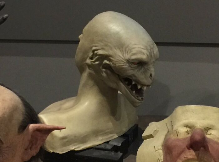 Alien-like creature bust displayed in a museum, showcasing how things used to look in imaginative historical designs.