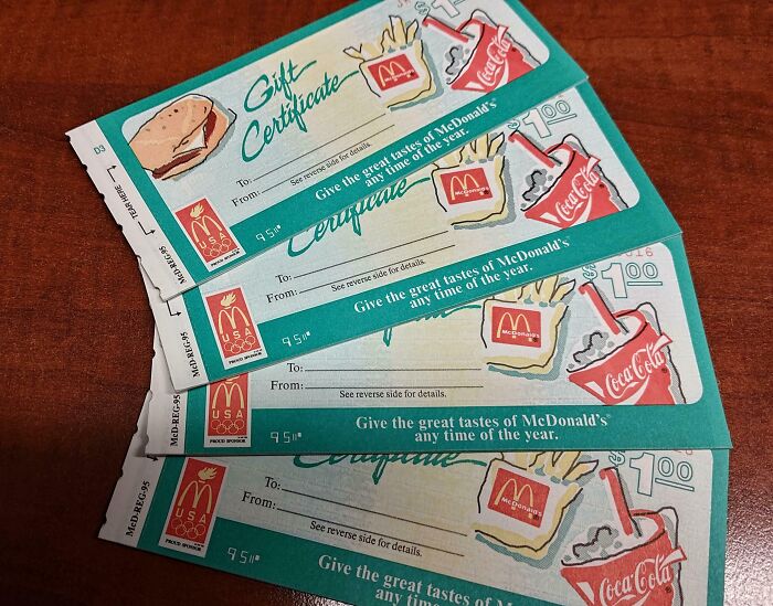 Vintage McDonald’s gift certificates with illustrations of fries, burger, and Coca-Cola on a wooden surface showing how things used to look.