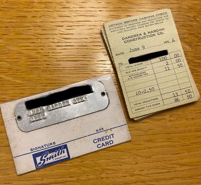 Vintage credit card and old paycheck stubs displayed on a wooden surface, showcasing how things used to look.