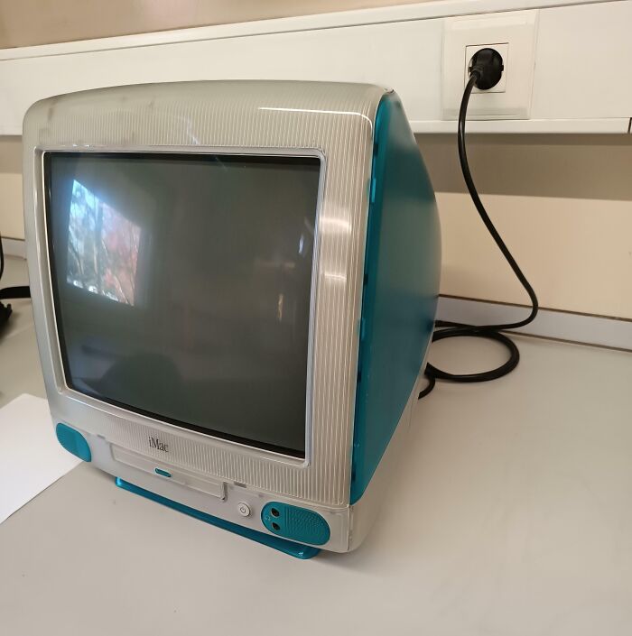 Vintage iMac computer on a white desk, showcasing how things used to look with classic technology design.