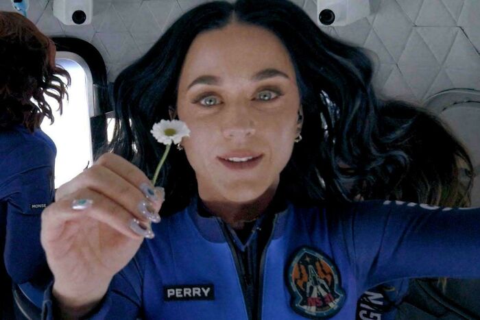 Woman in a blue NASA suit holding a flower, illustrating ways things have changed through the years according to people online.